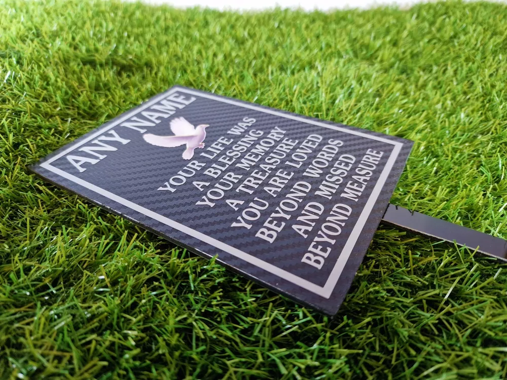 Rectangular memorial plaque with remembrance lettering and a ground stake.