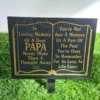 Black and gold papa plaque placed beside white grave flowers